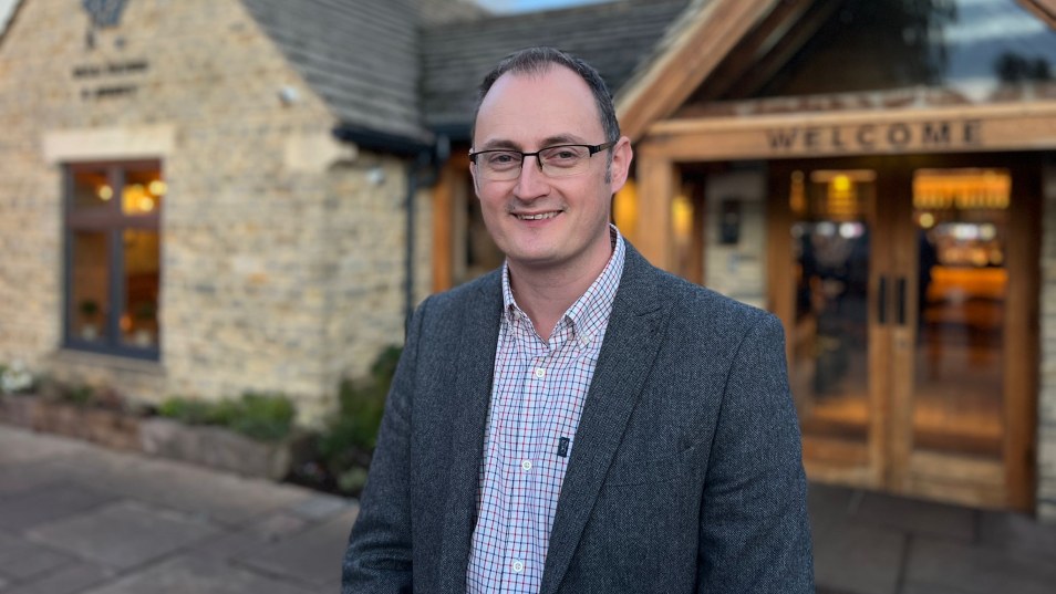 man in suit and glasses standing in front of hotel