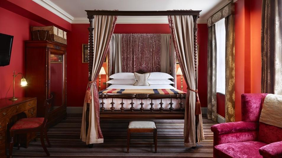 A four poster bed in a dark red room